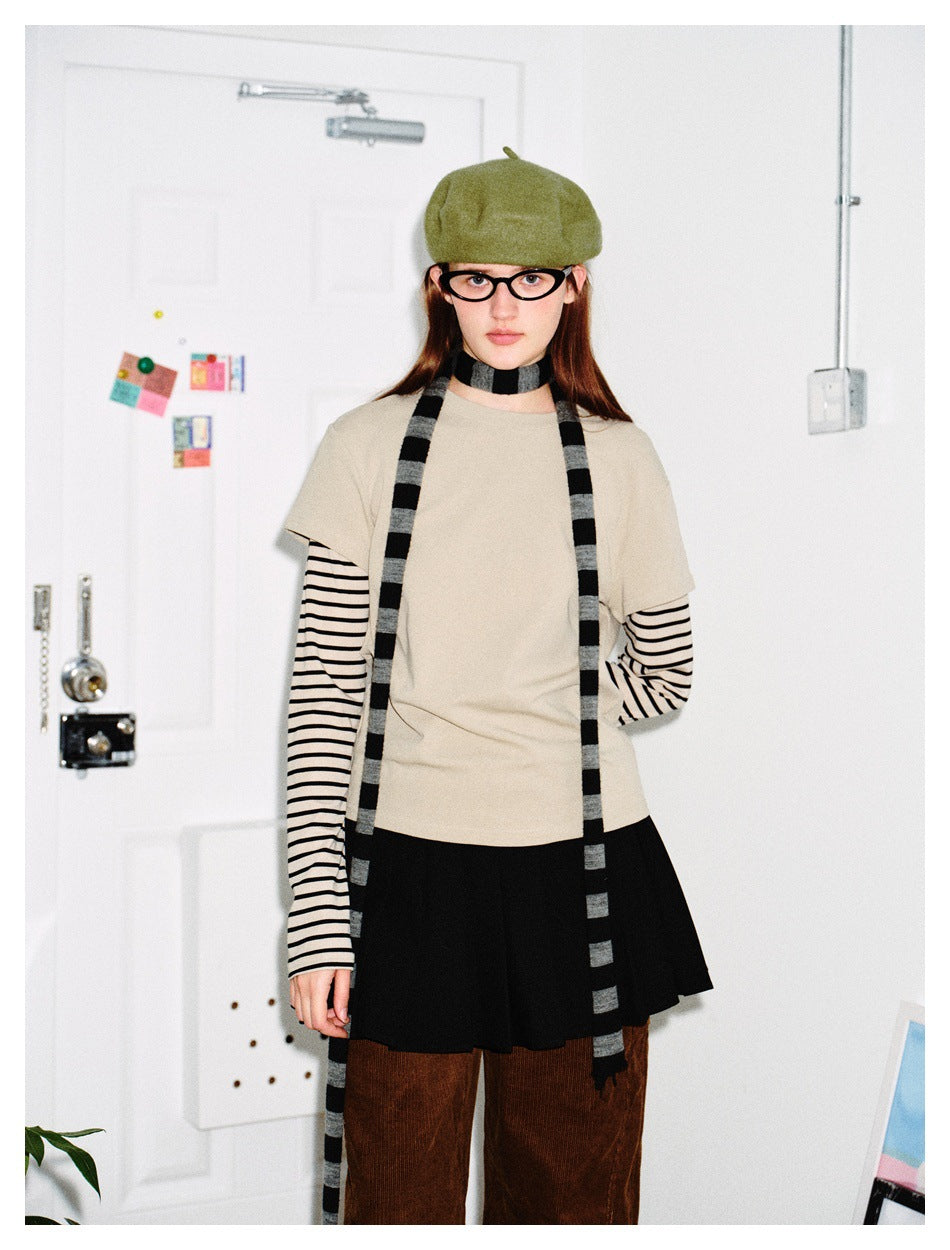 Model wearing the Apricot layered striped-sleeve top with a green beret, striped scarf and black pleated skirt, arms down