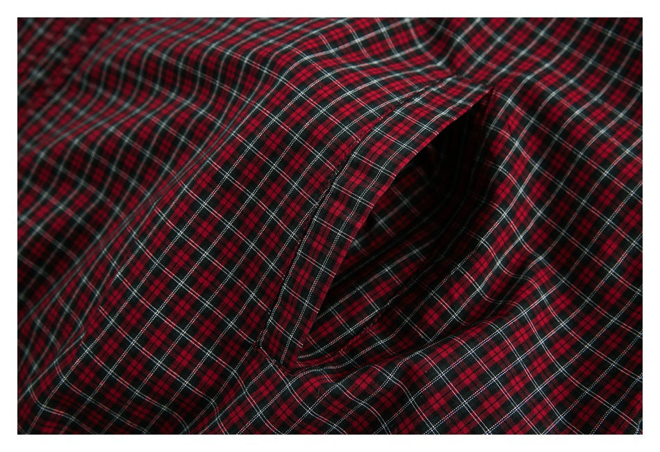 Close-up of red, black, and white plaid garment fabric folded around a dark opening.