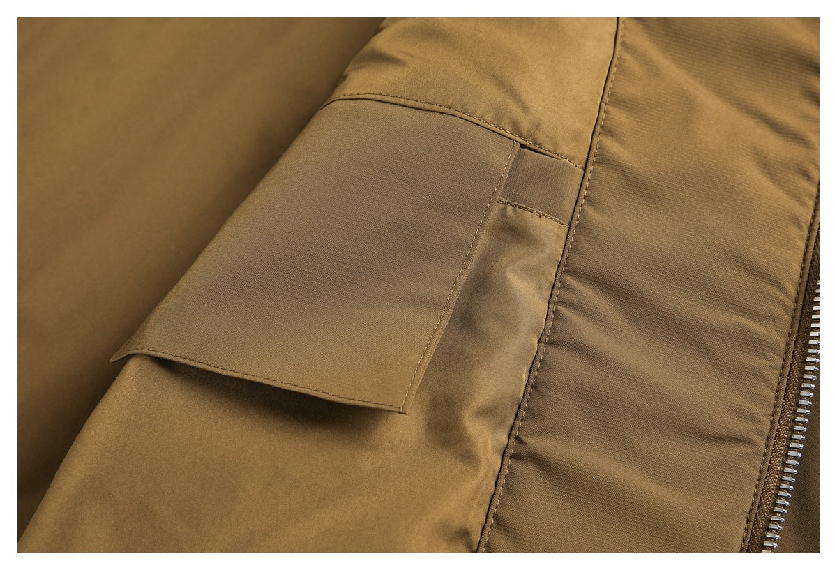 Close-up of a brown garment with a rectangular flap pocket, stitched panels, and a metal zipper.