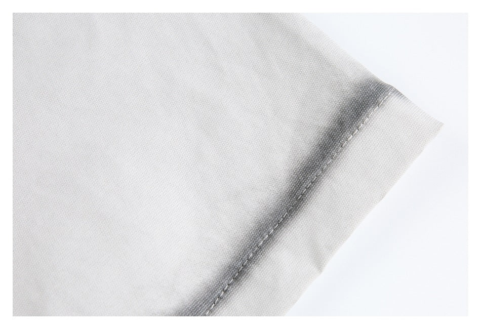 Close-up of a stitched edge on light gray fabric, showing a narrow folded hem.