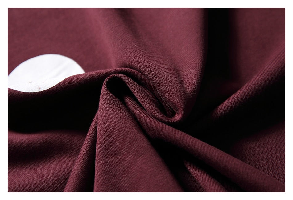 Close-up of deep burgundy fabric gathered into folds, with a small white area visible at the left.