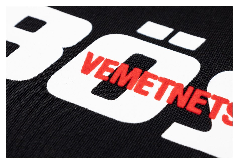 Close-up of white lettering and a raised red word graphic printed on black ribbed fabric.