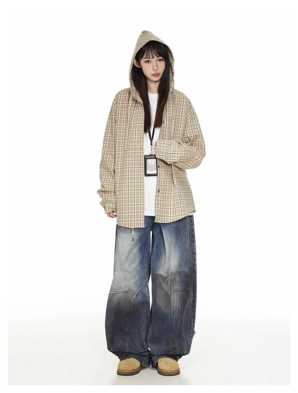 Full-length model wearing a beige plaid hooded overshirt, white top, and very wide blue jeans.