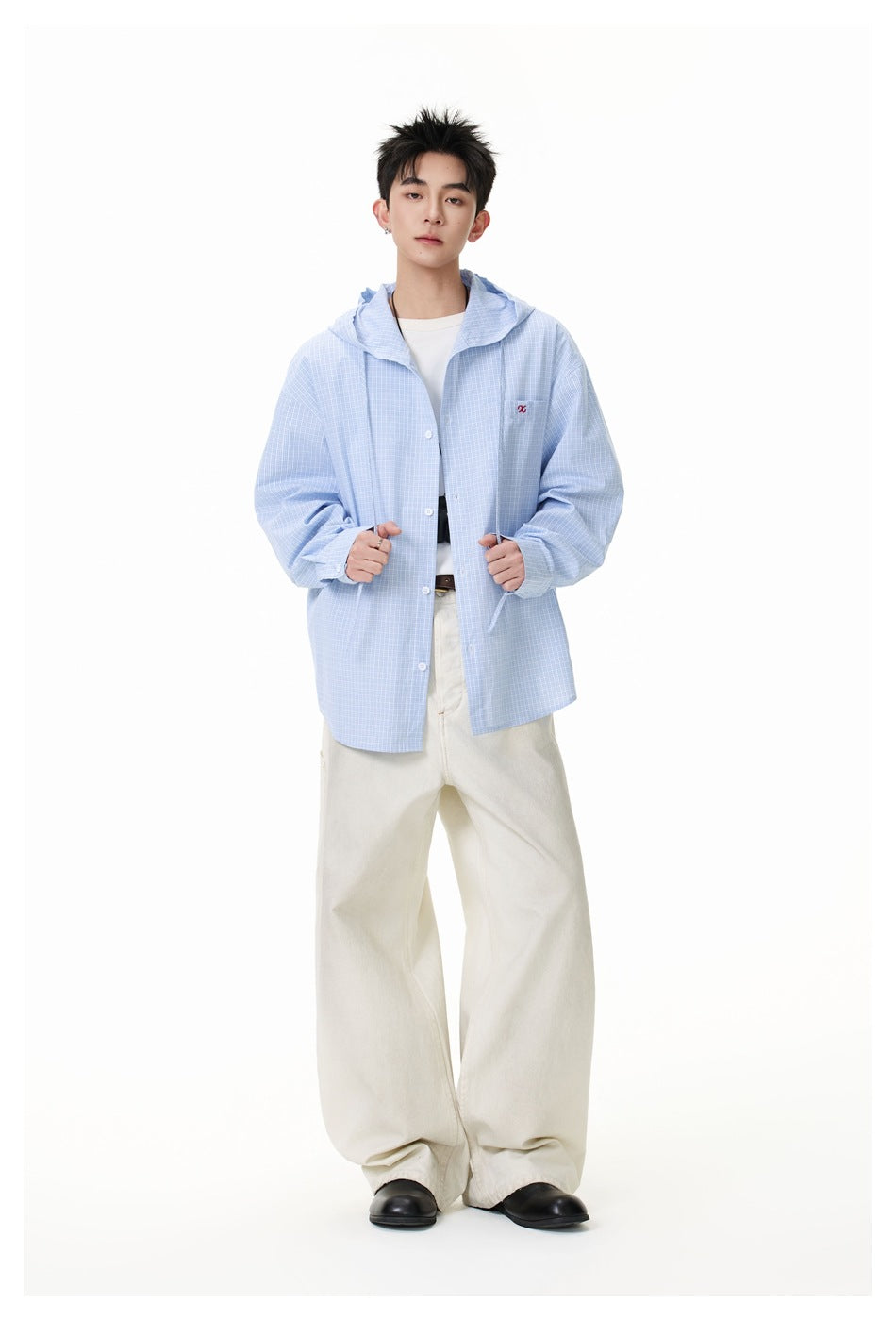 Model wearing a light blue small-check hooded button-up shirt open over a white tee with wide cream pants