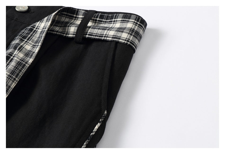 Close-up of black trousers with black-and-white plaid waistband lining and a button.