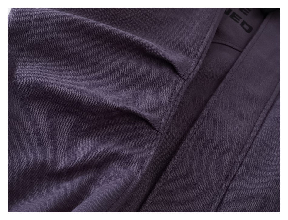 Close-up of dark plum textured fabric and seams, with a partial black mark visible on the inner garment.
