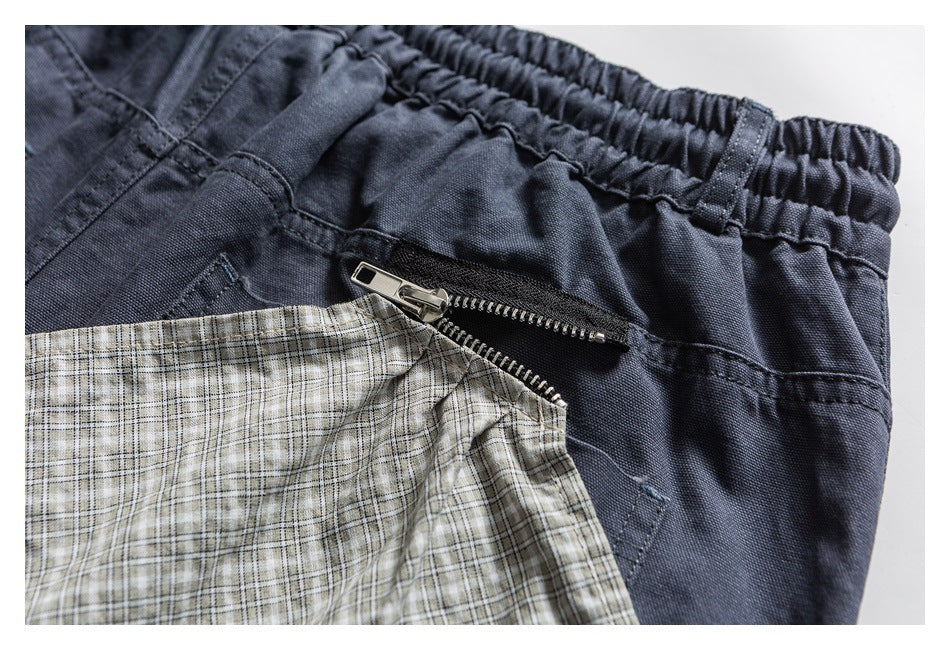 Close-up of dark shorts with an open metal zipper pocket and beige plaid lining.
