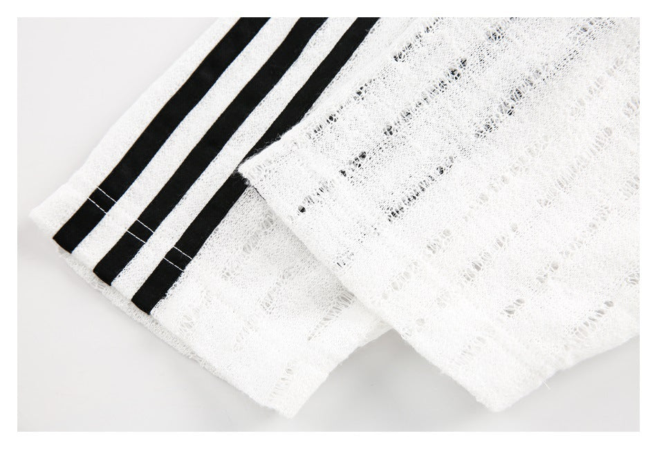 Close-up of a white open-knit hem with three black stripes and layered fabric edges.