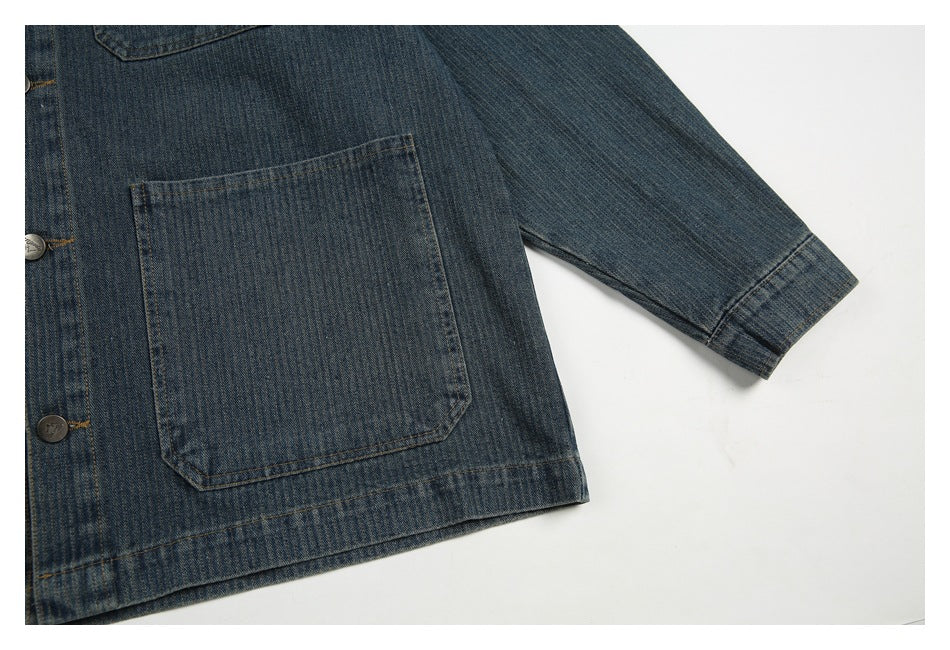 Close-up of a dark blue denim jacket's lower front pocket, hem, and buttoned sleeve cuff.