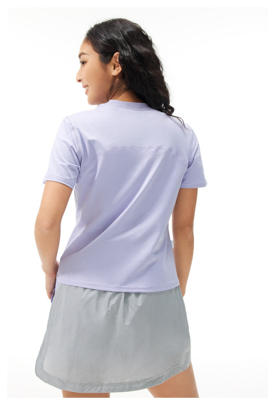 Back view of a model wearing a lavender short-sleeve T-shirt with a curved seam across the upper back.