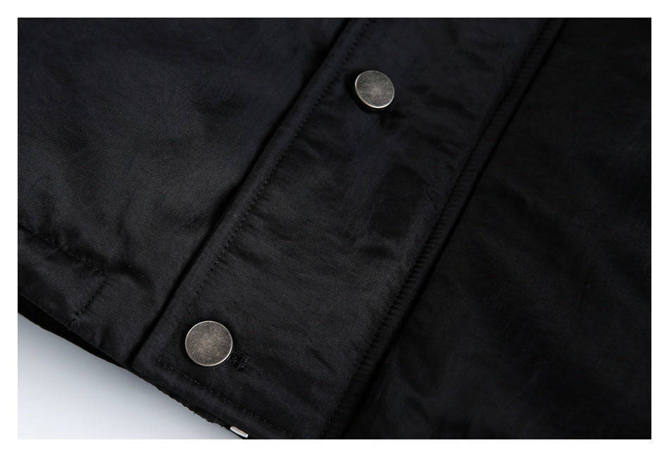 Close-up of a black jacket placket with two round metal snap buttons.