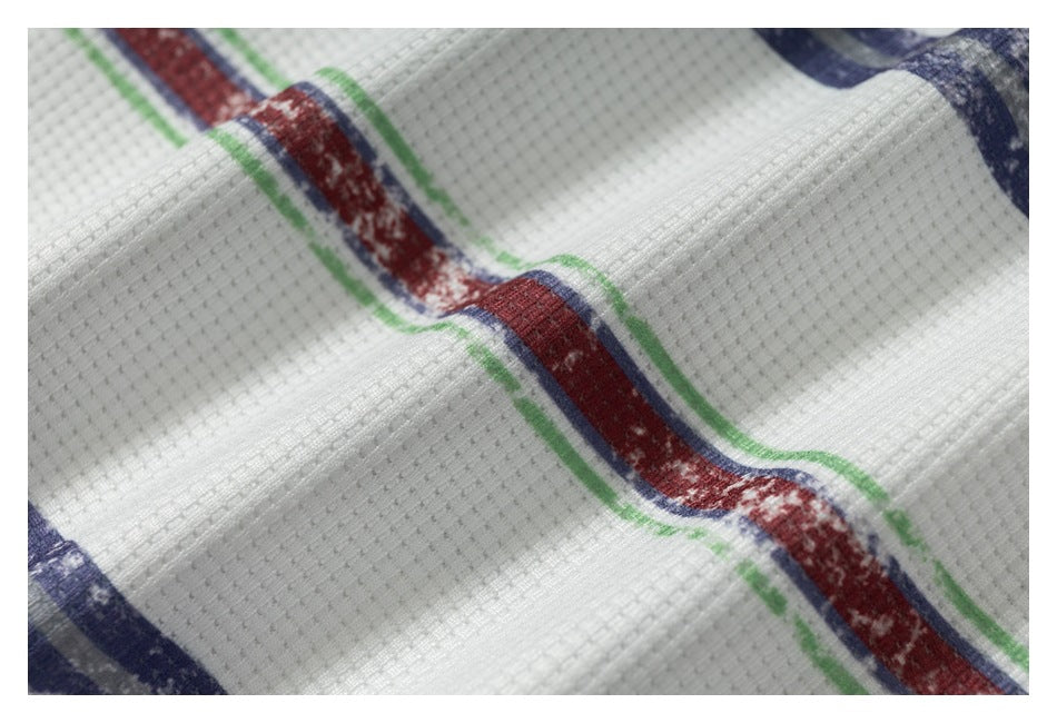 Close-up of white textured fabric with a wavy red stripe edged in green and navy.