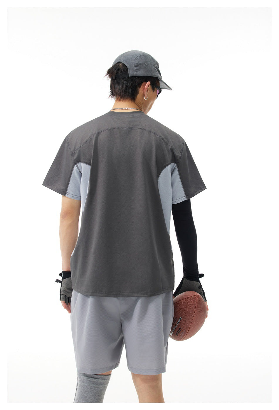 Back view of a model wearing a charcoal short-sleeve shirt with light gray side panels and gray shorts.