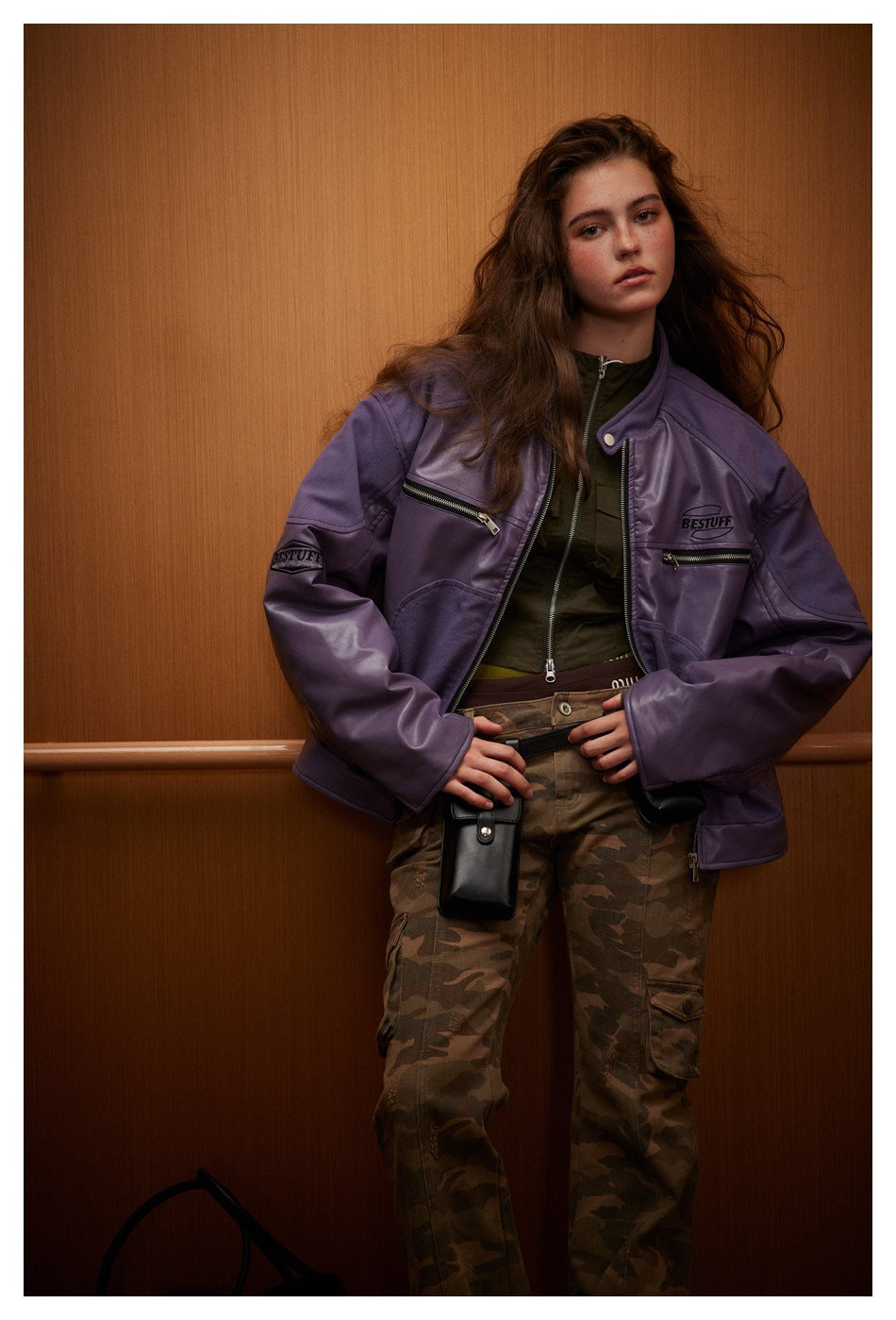 Model in a purple zip jacket with chest zippers and camouflage cargo pants.