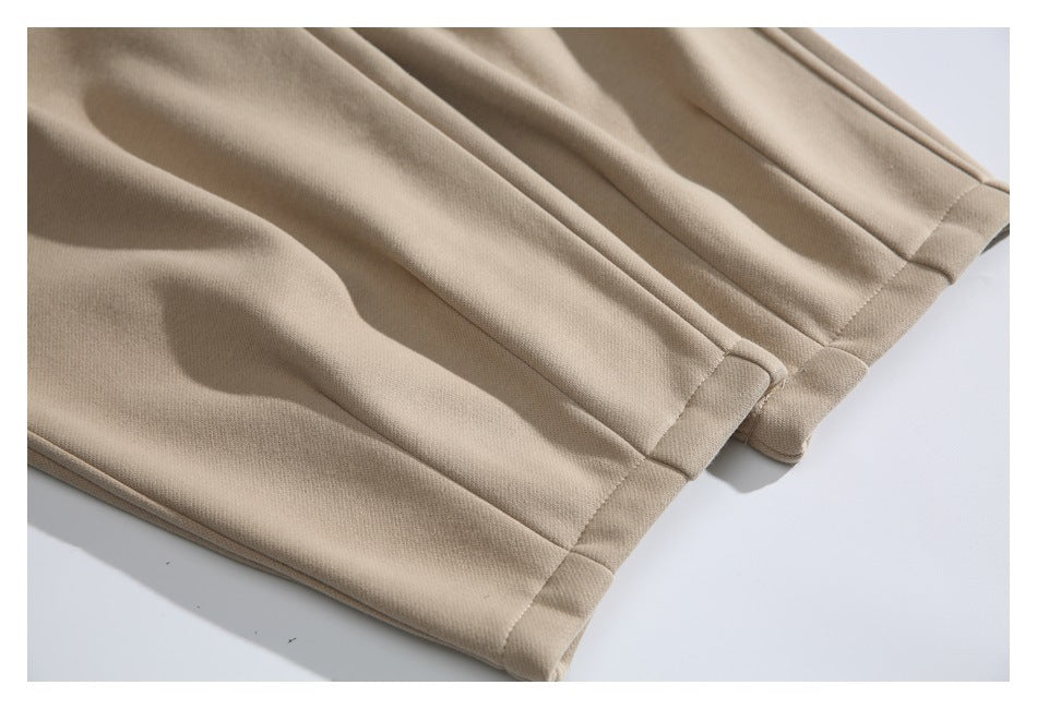 Close-up of beige pants leg hems with folded, stitched edges.