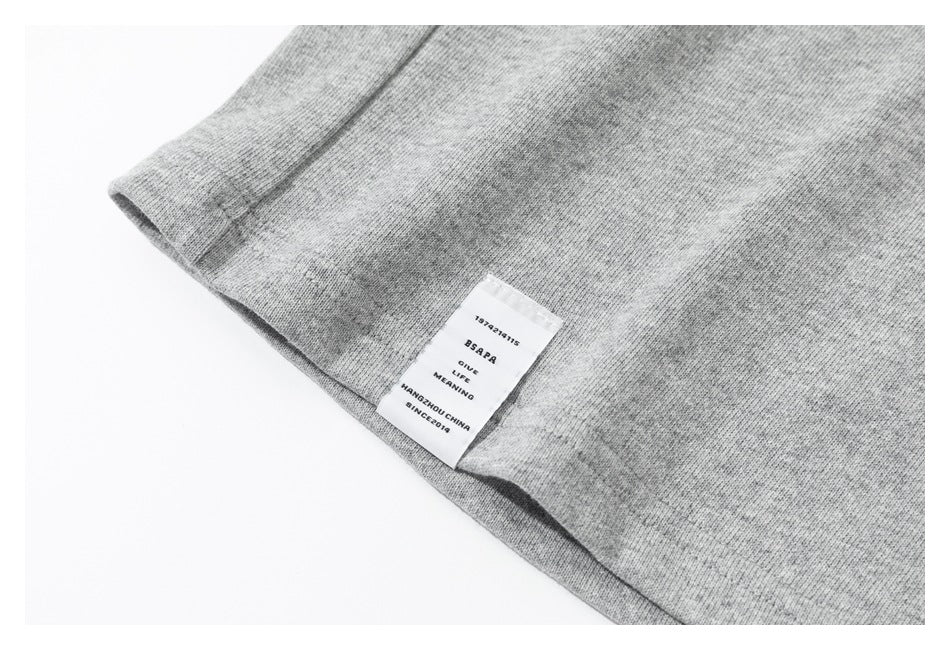 Close-up of a gray sweatshirt hem with a sewn-in white label bearing small English text.