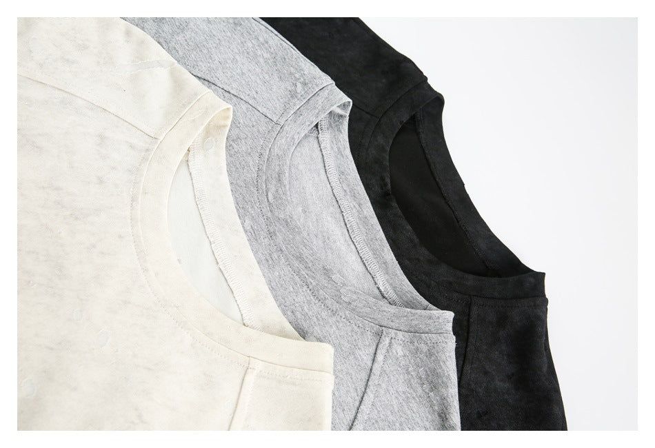 Close-up of the crew necklines and raglan seams on ivory, gray, and black T-shirts.