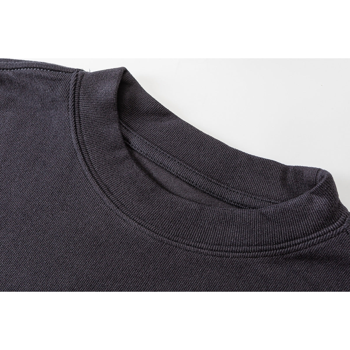 Close-up of the ribbed crew neckline and stitching on a dark charcoal long-sleeve top.