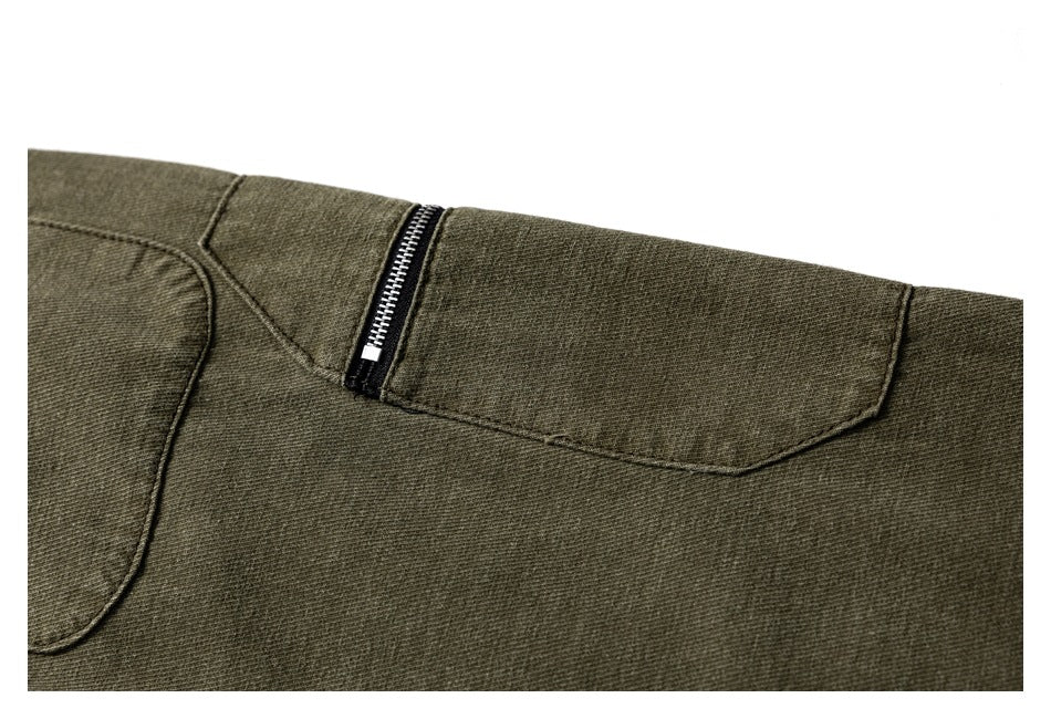 Close-up of olive trousers showing a black zipper and curved stitched panels.