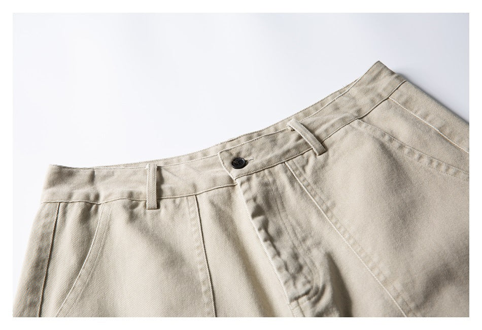 Close-up of beige shorts showing the waistband, belt loops, dark button, and front fly.