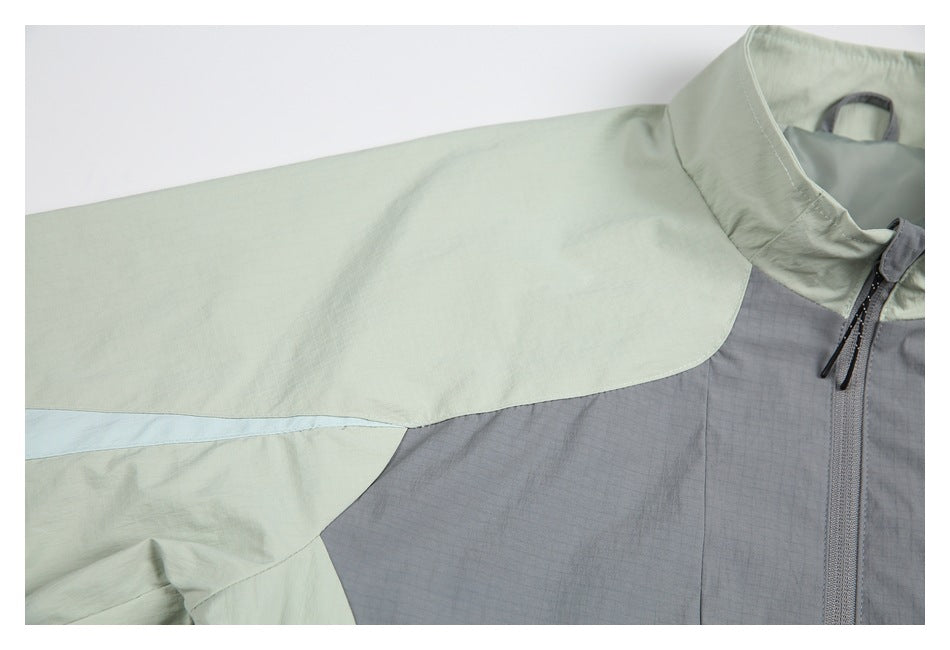 Close-up of the jacket's pale sage shoulder and sleeve panels beside the gray front and collar.