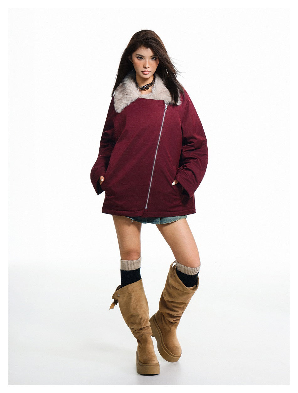 Model wearing a burgundy jacket zipped up with a light plush collar and a long diagonal zipper.