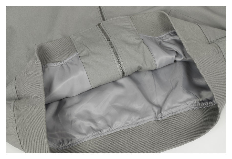 Gray jacket opened to show its smooth inner lining, zipper, and ribbed hem.