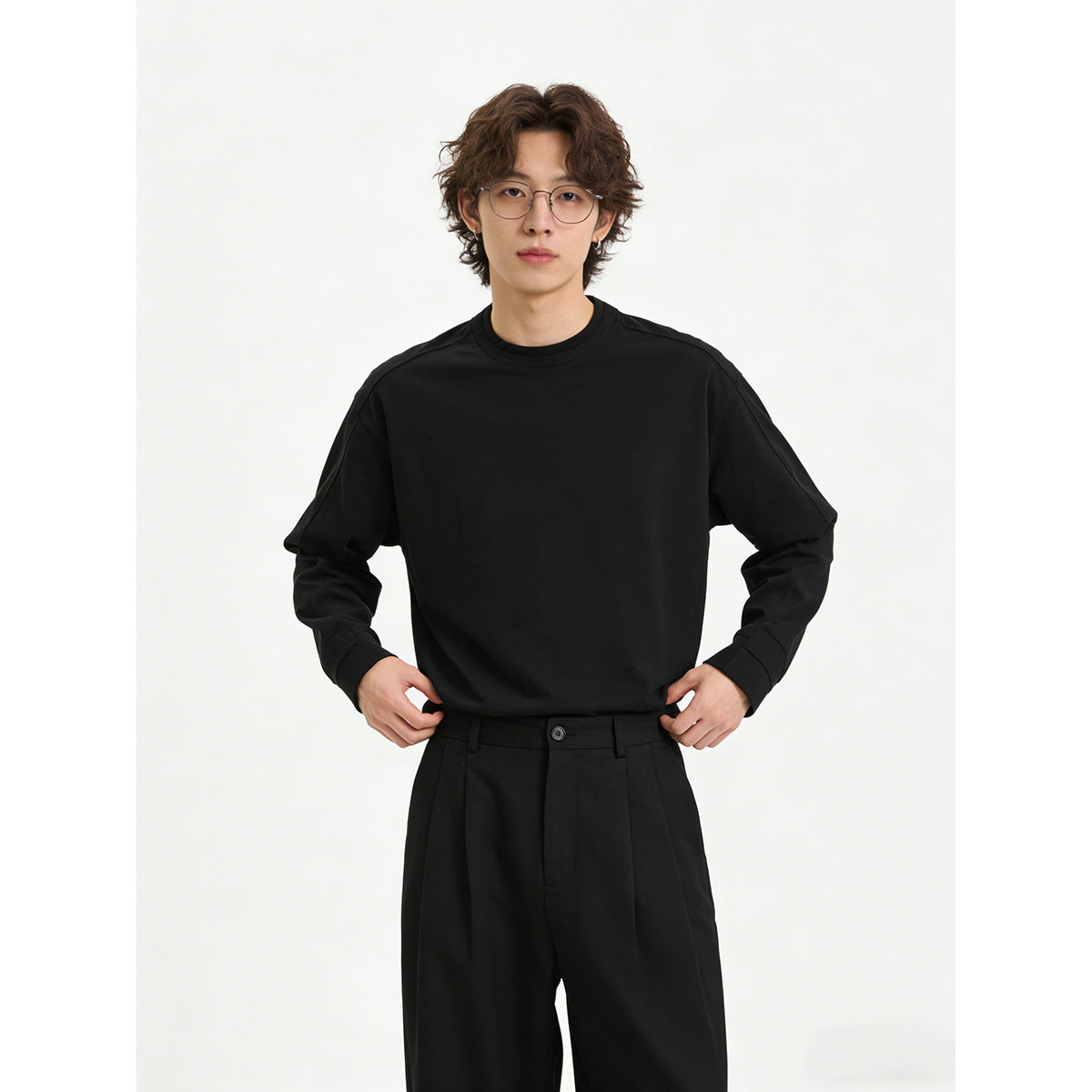 Model in a plain black crewneck sweatshirt, front view, with black trousers.