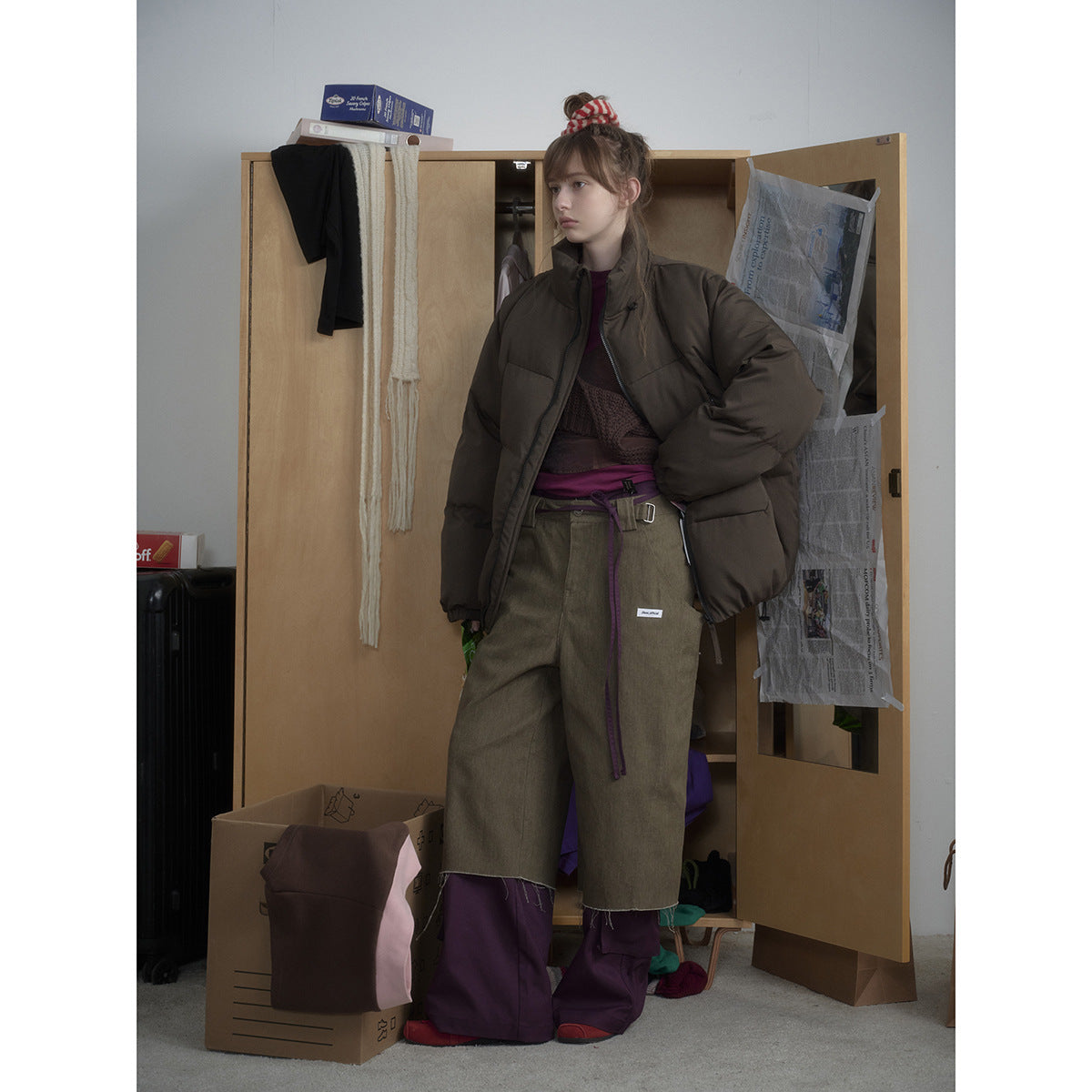 Full-length view of a model wearing a dark olive-brown puffer jacket and loose olive trousers.