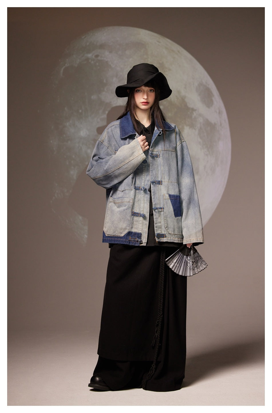Front view of a model in a loose gray denim jacket with a dark blue collar, patch pockets and loop closures.