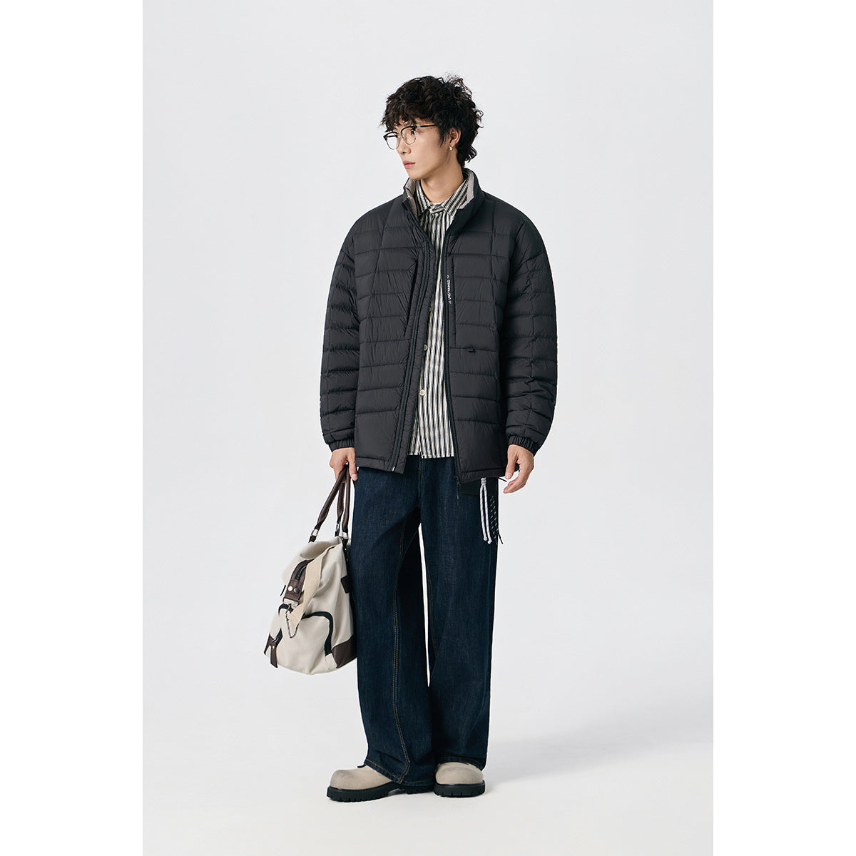 Model wearing a black quilted zip-up jacket with a stand collar and horizontal baffles.