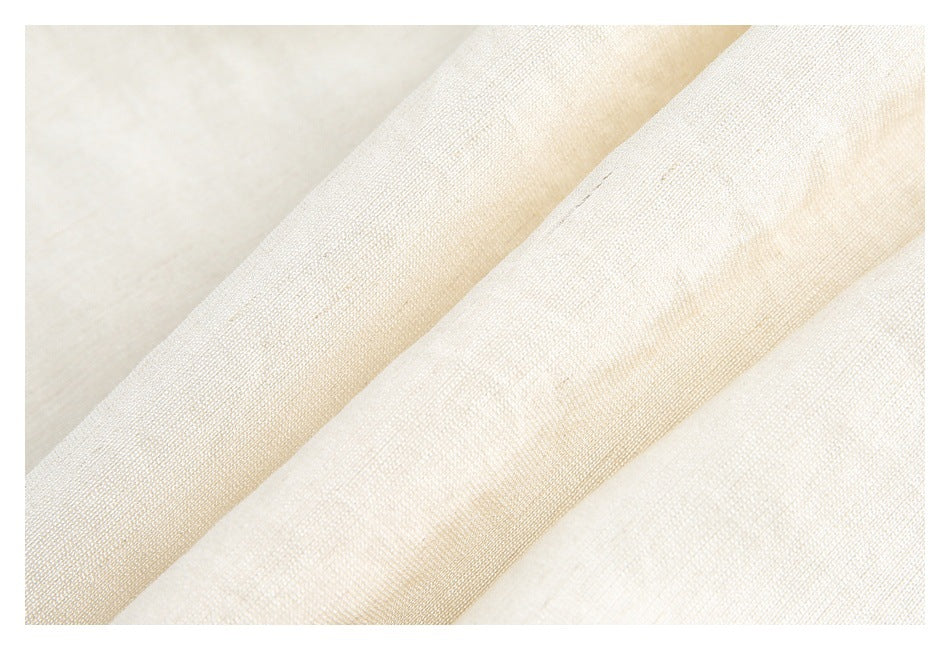 Macro view of the ivory shirt fabric, showing its fine woven texture and folds.