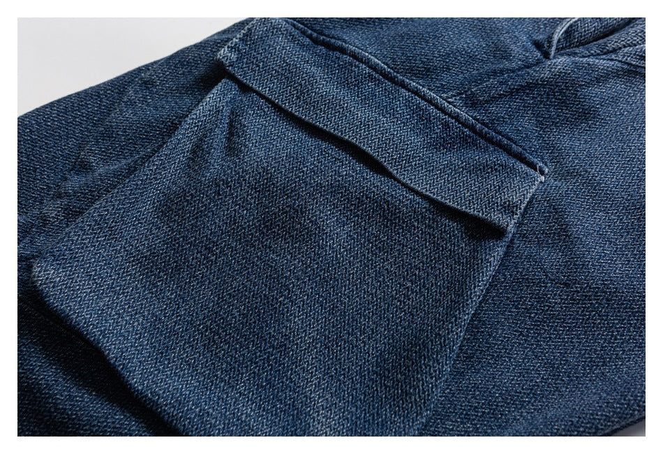 Close-up of a pocket opening and stitched denim panel on dark blue jeans.