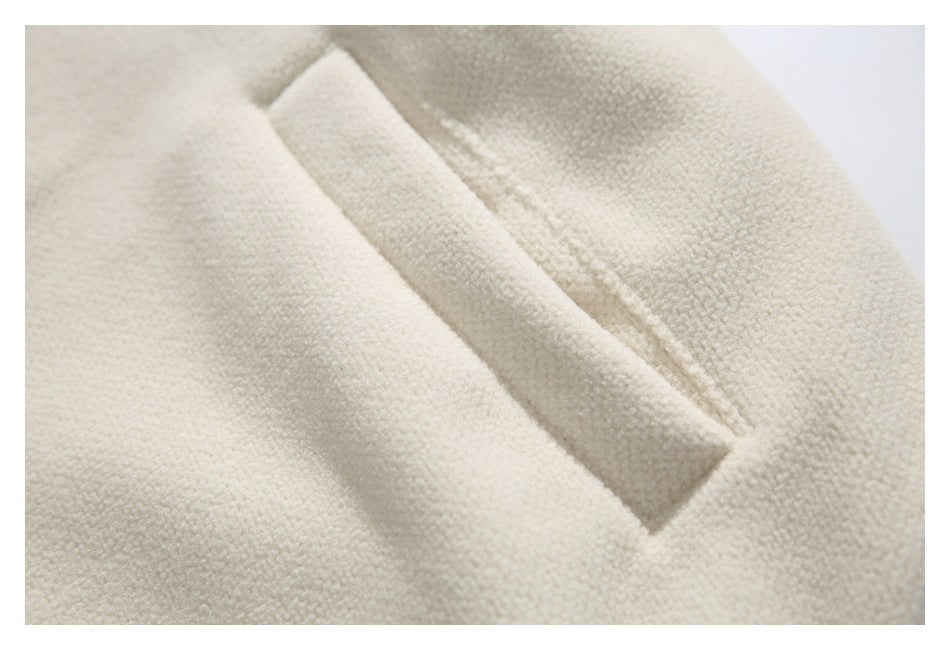 Close-up of a narrow welt pocket on cream textured fabric.