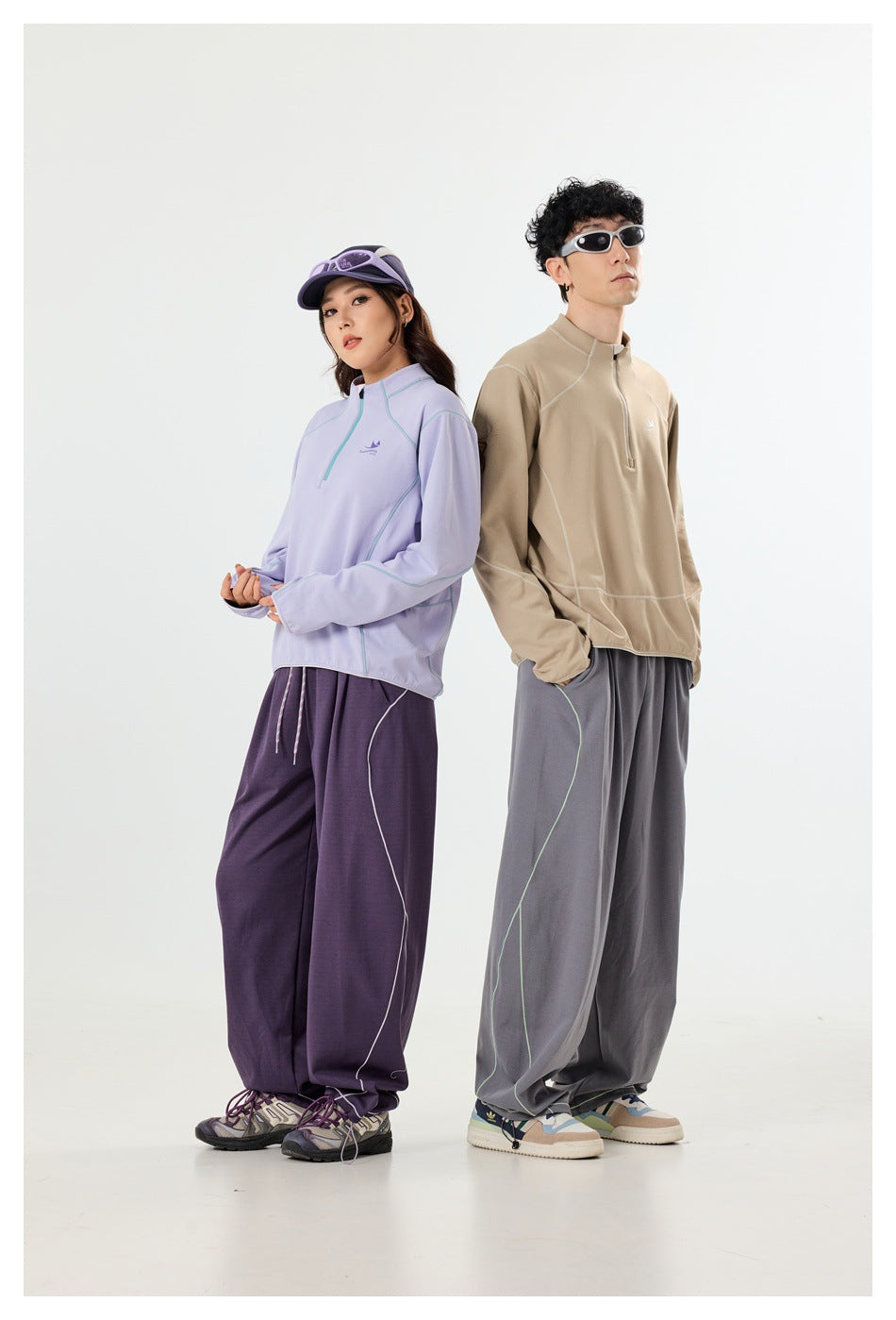 Two models wear a lavender quarter-zip pullover with purple pants and a tan pullover with gray pants.