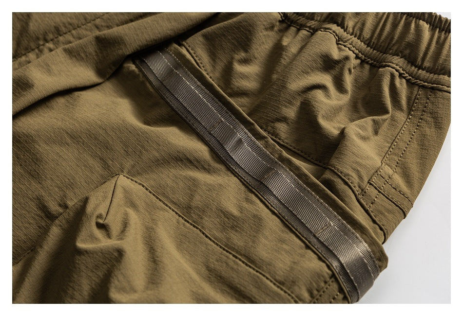 Close-up of olive-brown cargo shorts showing a flap pocket, stitching and a wide webbing trim.