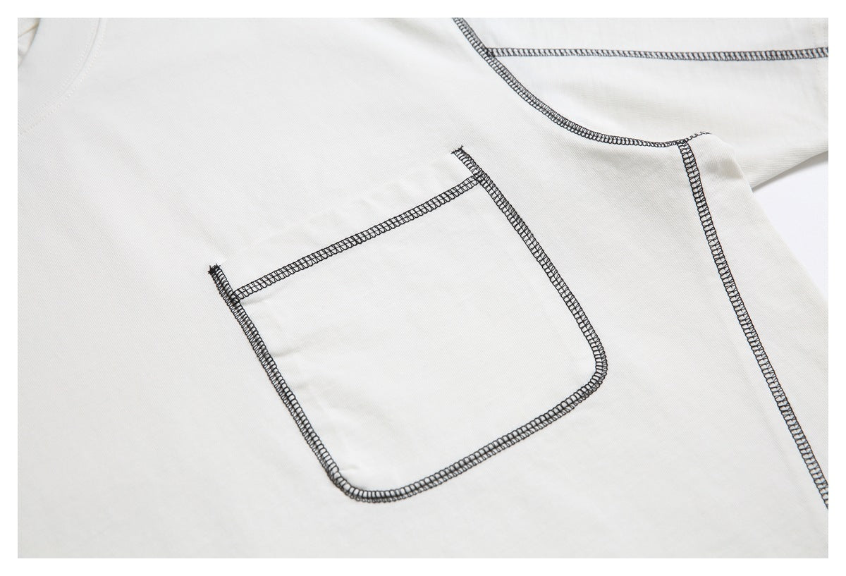 Close-up of a patch pocket and black contrast overlock stitching on an off-white T-shirt.