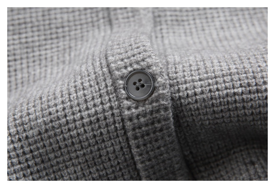 Close-up of a dark four-hole button and button band on a gray textured cardigan.