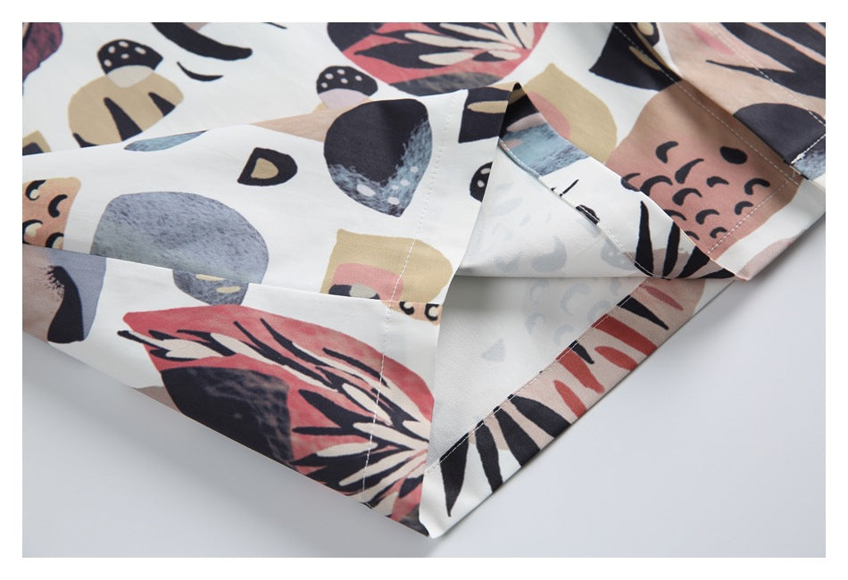 Close-up of a white garment with abstract multicolor print, showing a stitched edge and folded fabric.