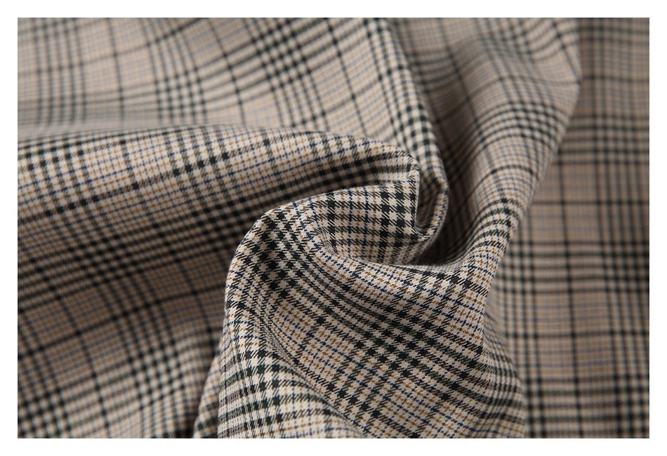 Close-up of draped beige, black, and blue plaid fabric showing its woven check pattern.