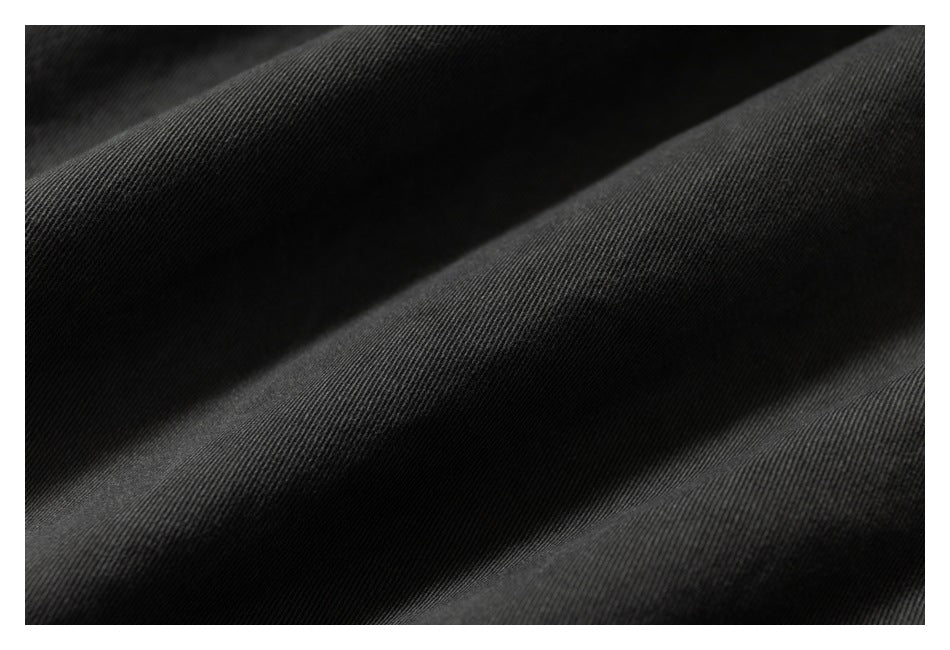 Macro view of dark charcoal fabric folded into soft ridges, showing its fine woven texture.