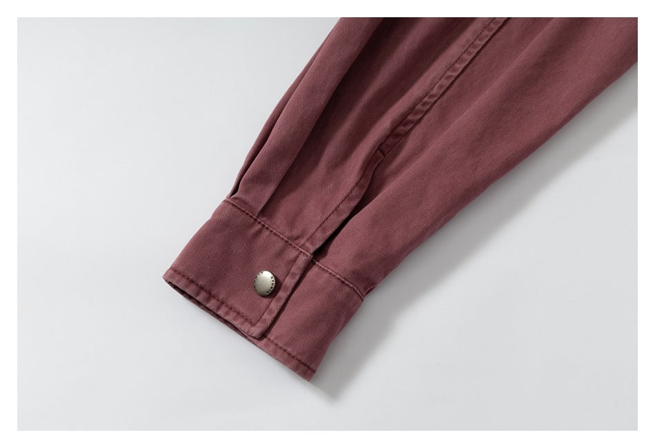 Close-up of a dusty rose sleeve cuff with a metal snap button and stitched seam.