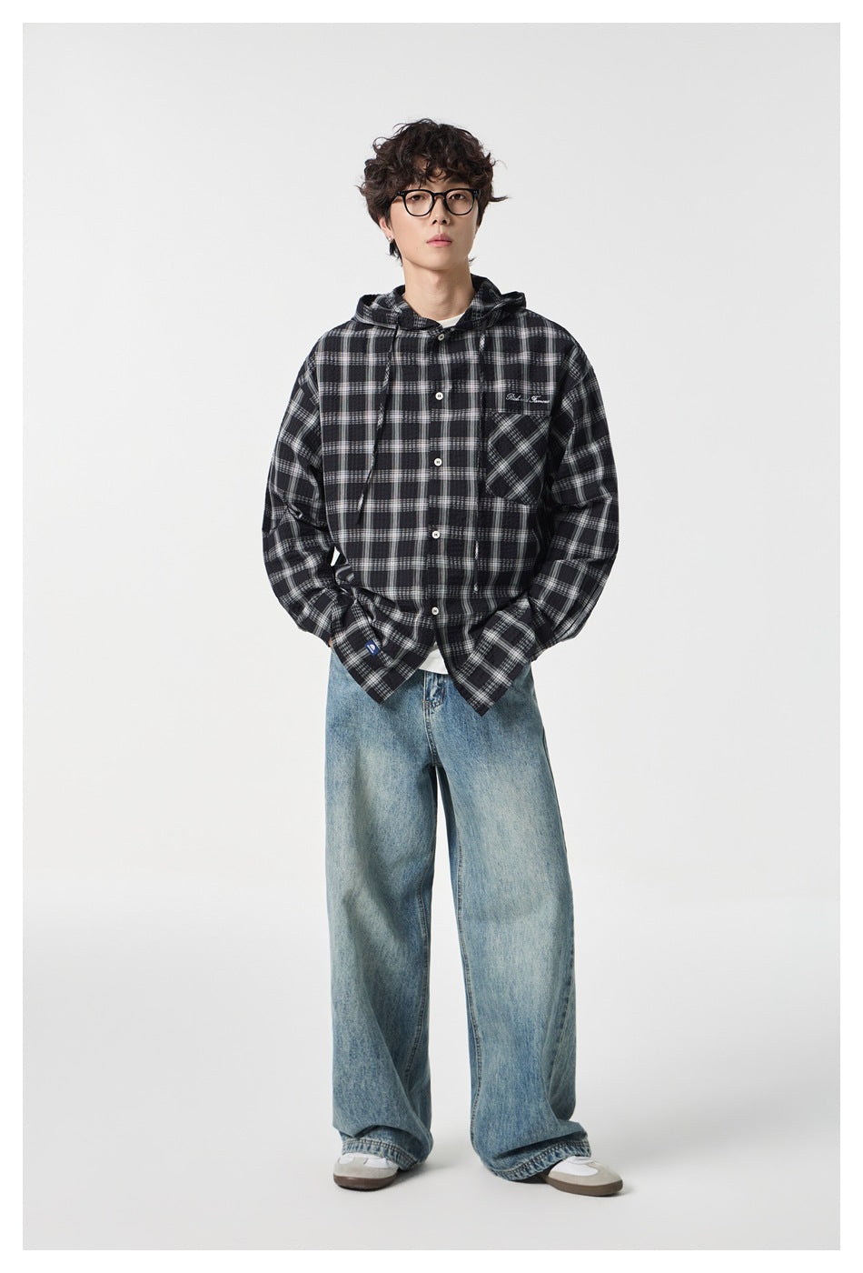 Full-length model wearing a black-and-white plaid hooded button-up shirt with blue jeans.