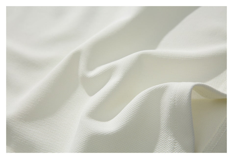 Close-up of the ivory garment fabric, showing its fine textured surface and folds.