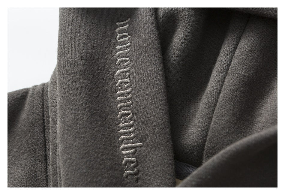 Close-up of raised embroidered lettering along the edge of a charcoal hoodie.