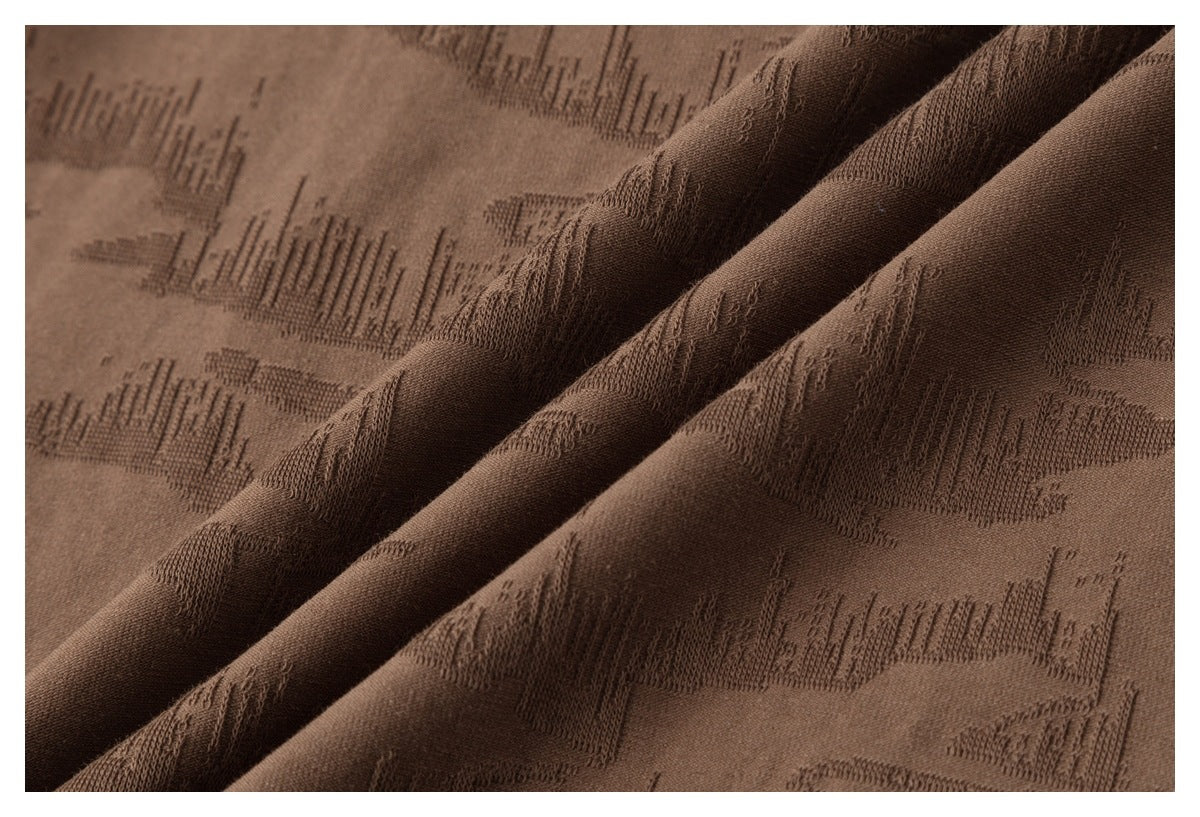 Close-up of brown fabric draped into folds, highlighting its raised geometric texture.