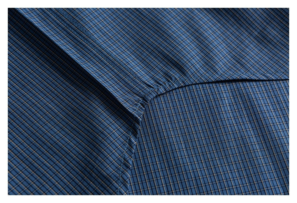 Close-up of blue plaid shirt fabric and a curved stitched seam.