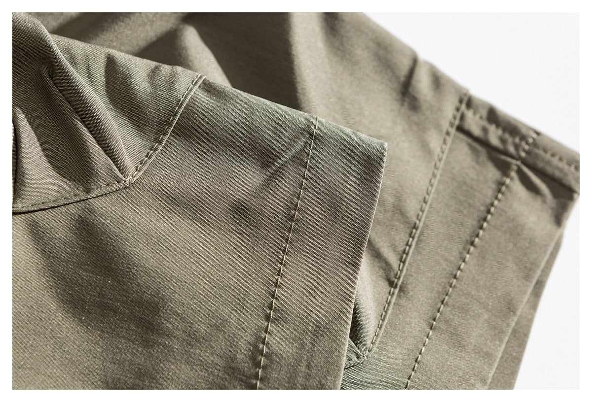 Close-up of khaki trouser fabric showing a pocket edge and parallel stitched seams.
