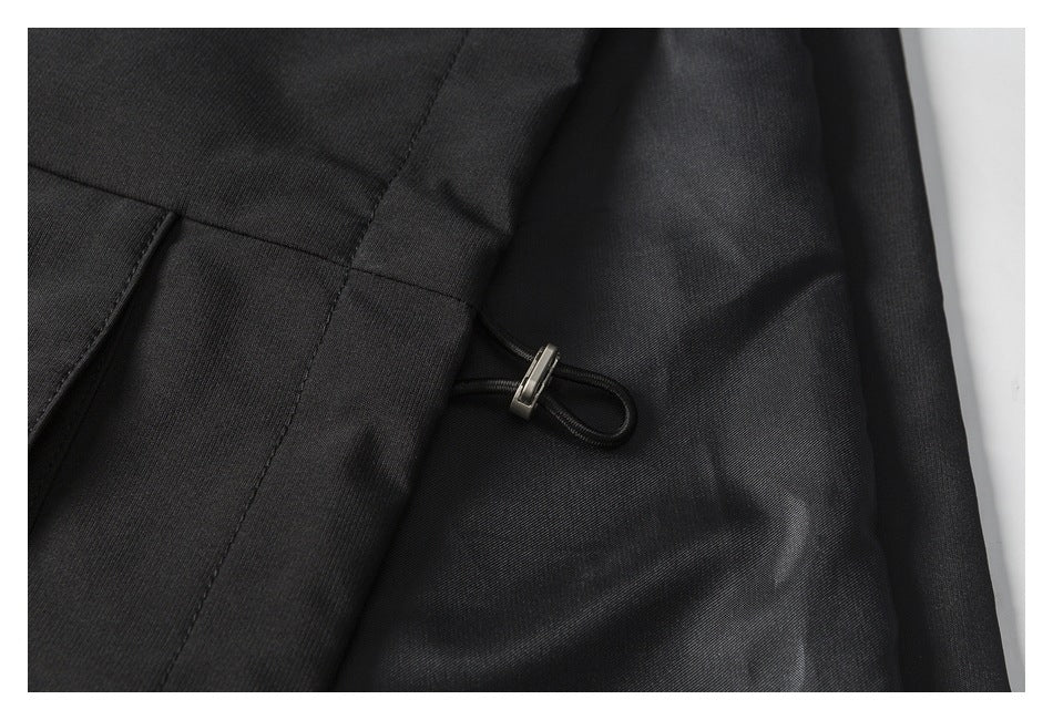 Close-up of a black jacket with a small loop and metal toggle beside a seam.