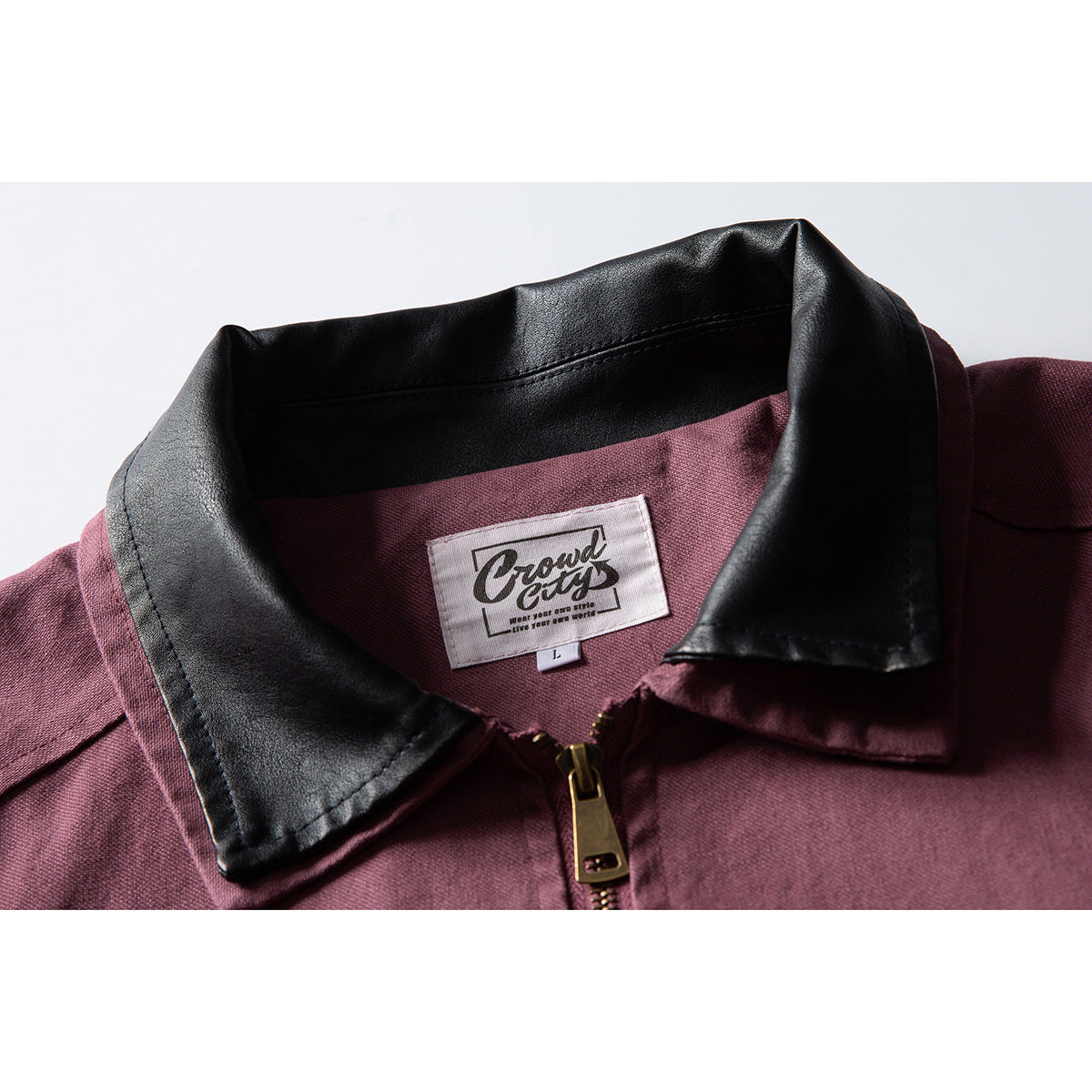 Close-up of a burgundy jacket with a black collar, front zipper, and visible neck label.